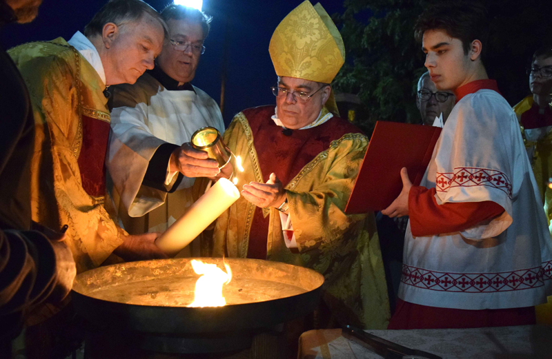 Bishop of Allentown Alfred Schlert, second from right, lights the paschal candle during the Easter Vigil on Holy Saturday, March 31 at the Cathedral of St. Catharine of Siena, Allentown. Assisting him in lighting the new fire, symbolizing eternal life in Christ, are from left, Deacon Robert Snyder and master of ceremonies Monsignor Victor Finelli. (Photos by John Simitz)