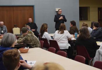 Msgr. Victor Finelli welcomes parents and teens to “Protecting Our Teens,” a discussion about teen mental health and suicide prevention May 30 at St. Francis of Assisi, Allentown. Seated from left are Randy Rice and Father Allen Hoffa. (Photo by John Simitz)