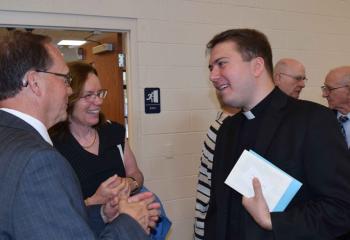 Father John Rother greets Mark Roth and Rosemary Leblond, parishioners of St. Thomas More, Allentown. (Photo by John Simitz)