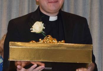 Father John Rother displays gifts given to him by Serrans. (Photo by John Simitz)