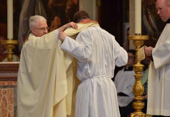 Father William Linkchorst, left, pastor emeritus of SS. Peter and Paul, Tamaqua, vests Father Rother with a stole as a sign of his authority to act in the name of Christ during Investiture with Stole and Chasuble. (Photo by John Simitz)
