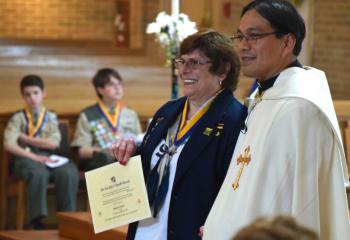 Joanne Loeper receives the For God and Youth Award from Father Eric Tolentino. (Photo by John Simitz)
