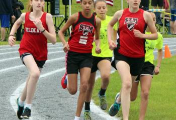 Girls run in a pack while competing in the track and field meet.