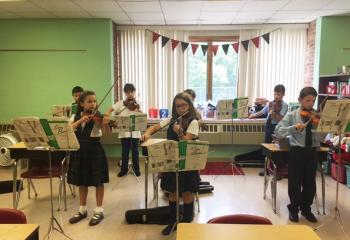 Practicing during violin lessons May 31 are, from left: front, Lily Snyder, Olivia Lesher and Colten Brown; back, Paul Zuk, Nicole Knoblauch, Dalton Seisler and Aidan Becker. (Photo courtesy of St. Ambrose School)