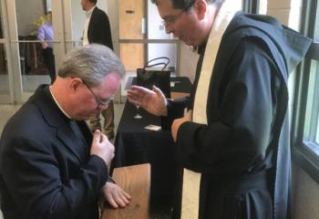 Benedictine Father Linus Klucsarits (formerly Paul Klucsarits) offers his first priestly blessing to Msgr. Andrew Baker at the reception after Father Linus’ ordination to the priesthood June 3 at St. Bernard’s Abbey Church, Cullman, Alabama. (Photo courtesy of Msgr. Andrew Baker)