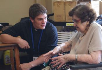 Seminarian Keaton Eidle chats with Holy Family Manor resident Mary Vidonya during the July 18 afternoon visit. (Photo by John Simitz)