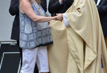 Beth Bakes, left, parishioner of MBS, is greeted by Father Michael Paul at the celebration in the new plaza.