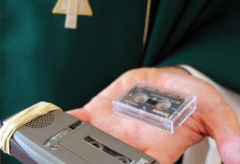 Father Bernard J. Ezaki, parochial vicar at St. Jane Frances de Chantal Church in Easton, Pa., holds the micro-cassette recorder that he uses for Mass prayers, the homily and readings when he celebrates Mass. (CNS photo/Ed Koskey Jr.) 