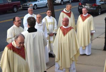 Priests and deacons gather before the Mass.