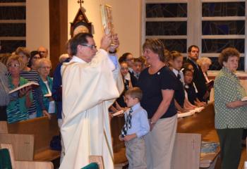 Deacon Robert Young of St. Francis of Assisi processes into the evening Mass carrying the Book of the Gospels.