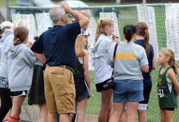 Participants and coaches check race results posted on a fence at the meet.