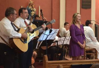 Jessica Jansson sings a hymn with a string quartet during Holy Communion. A 50-member deanery choir joined together to practice for several weeks before performing selections at the Mass.