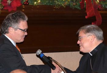 John Boyer, left, announces the chapter’s $500 donation to the Retired Priests’ Fund in Bishop Alfred Schlert’s name.