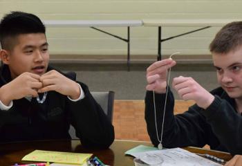 Andrew Nguyen, left, and Griffin Curtin assemble rosaries during the rally. (Photo by John Simitz)