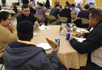 Father Angel Garcia Almodovar, center, pastor of St. Margaret, Reading, enjoys pizza with the family of a young man interested in learning more about vocations.