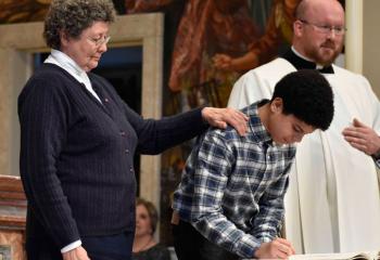 Joseuien Aceuedo becomes “elect” after signing the Book of the Elect under guidance from Sister Margaret Pavluchuck, director of religious education at St. Peter the Apostle, Reading.  