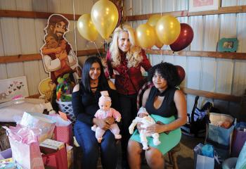 Surrounded by gifts, Maggie Sweet stands with Nashaly Cruz Pagon, seated left, and Shannet Cuascut holding her 6-day-old son Jaivian Rosario Oct. 22 at a baby shower for the two young women that was organized by pro-life members of Forty Days for Life and Silent No More from the Lehigh Valley and Norristown. (Photo by Ed Koskey)