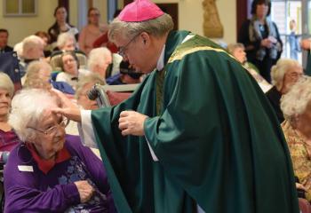 Bishop Schlert anoints Ruth Neff with blessed oil while performing the Sacrament of the Anointing of the Sick.