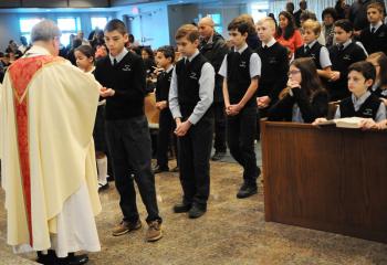 Bishop Alfred Schlert distributes the Eucharist to sixth-graders at Our Lady of Perpetual Help School, Bethlehem during a special Mass highlighting the faith, gifts and talents of Catholic schools students and staff. From left are Cade Santos, Matthew Frio, Lyubomir Tonev, Cole Griffin, Alex Miner, Santo Raneri and Matthew Morales. (Photo by Ed Koskey)