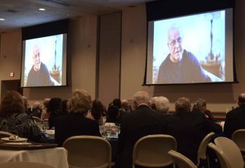 Charles Klinesmith is on the screen during the Catholic Charities video.