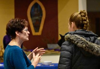 Addiction Ministry Team member Donna, left, welcomes a woman to the evening.