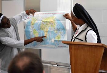 Missionary Sisters of the Precious Blood Sister Lucy Kawau, left, and Sister Anastasia Mallya show the group a map of where they serve in Africa.