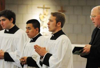 Monsignor David James, right, diocesan vicar general and director of the Office of Vocations, prays with diocesan seminarians, from left, Alexander Brown, Leiser Ramirez and Aaron Scheidel.