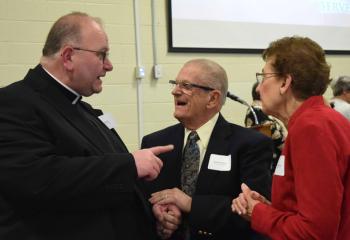 Father Eric Arnout, pastor of Assumption BVM, Slatington, chats with Robert and Mary Ann Kulhamer, parishioners of St. Elizabeth of Hungary, Whitehall, about the programs and services made possible through BAA.
