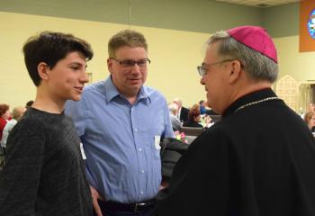 Andrew LaRock, left, and his father Michael LaRock enjoy a conversation with Bishop Schlert at the kickoff celebration.