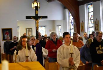 Deacon John Setlock processes into St. Richard carrying the crucified Christ as the faithful stand in silence to begin Good Friday service.