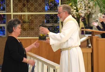 Deacon Hugh Carlin accepts the Oil of the Sick from Jane Magdasy during Reception of the Holy Oils on Holy Thursday at Sacred Heart, Bethlehem. Parishioners also presented Holy Chrism Oil and Oil of the Catechumens that were prepared and transported from the Cathedral of St. Catharine of Siena, Allentown.