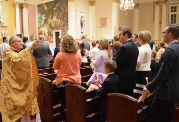 Monsignor Francis Schoenauer, pastor of the cathedral, blesses the faithful as they renew their baptismal promises during the Liturgy of Baptism at the Easter Vigil.
