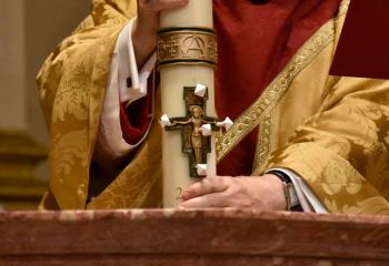 Bishop Schlert immerses the paschal candle in holy water after placing five grains of incense into the candle.