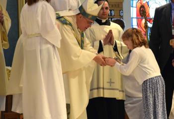 Emma Kate Oswald, parishioner of St. Ignatius, presents the offertory gifts to Bishop Schlert.