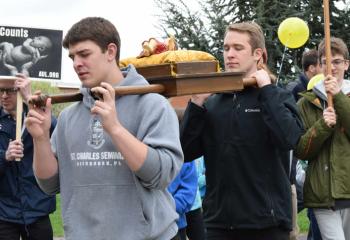 Keaton Eidle, left, and Aaron Scheidel, diocesan seminarians, carry the baby Jesus during the march.