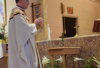 Father Robert Finlan, pastor of St. Joseph, Frackville, blesses the Traveling Vocations Crucifix to be hosted by a different parish family each month to increase prayers for vocations to the priesthood and religious life. 