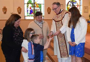 Father Finlan presents the Kowalonek family with the Traveling Vocations Crucifix to take to their home. From left are Jennifer, Claire, Francis, Stefan and Alyza. 