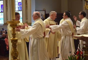Deacons welcome the newly ordained at the Kiss of Peace.