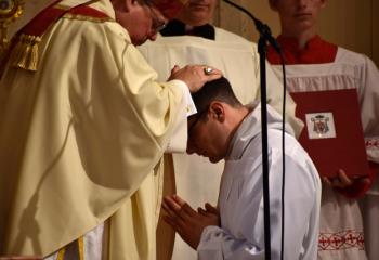 Bishop Alfred Schlert imposes his hands on candidate Giuseppe Esposito, which is the outward sign of the Sacrament of Holy Orders.