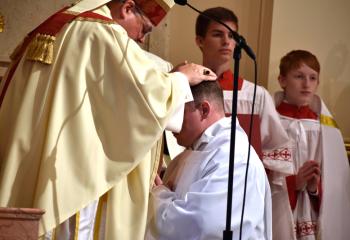 Bishop Alfred Schlert imposes his hands on candidate Zachary Wehr, which is the outward sign of the Sacrament of Holy Orders.