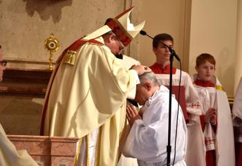 Bishop Alfred Schlert imposes his hands on candidate John Maria, which is the outward sign of the Sacrament of Holy Orders.