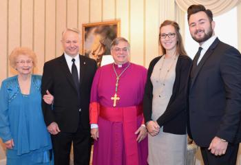 Bishop Alfred Schlert greets the Maria family before the liturgy, from left, mother Theresa Maria, deacon candidate John Maria, and daughter-in-law and son Abby and James Maria.