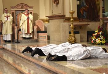 Bishop Alfred Schlert and Deacon John Hutta, left, sing the Litany of Supplication (Litany of Saints) as the candidates prostrate themselves before the altar.