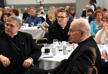 Listening to Father William Campion speak are, from left, Bishop Alfred Schlert, Father John Hutta, Anne Girard and Bishop Emeritus Edward Cullen. (Photo by John Simitz)