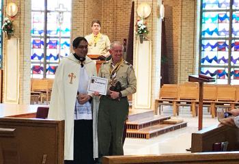 Father Eric Tolentino, left, presents the Rev. Joseph Campbell Award to Fred Flemming. Randy Bjorken watches from the lectern.