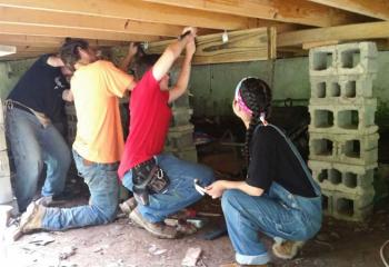 Students work to install a new grinder on a home in West Virginia, from left, site chaperone Chris Frye, Griffin Cournan, Tim Pozerski and Alyanna Dusaban.