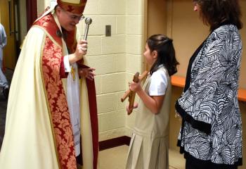 Bishop Schlert, left, blesses the fourth grade crucifix being held by Kaitlyn Purin.