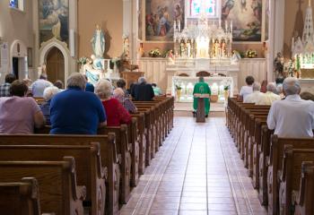 Barnabite Father Robert Kosek, pastor of St. John the Baptist, Allentown, prays with parishioners in front of the Blessed Sacrament. (Photo by Sue Braff)