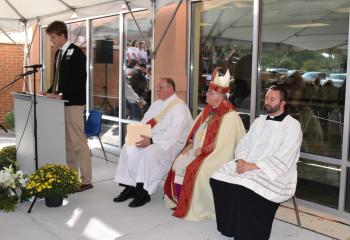 Luke Painton serves as lector. Listening are, from left, Deacon Rick Lanciano, Bishop Alfred Schlert and Father Stephan Isaac.
