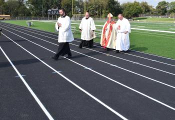 Bishop Alfred Schlert walks the track after the blessing with, from left, Father Stephan Isaac, Father Eugene Ritz and Deacon Rick Lanciano.